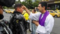  Mientras cumplen con su labor de mantener el orden en la ciudad el presbítero Juan Felipe Escobar impone la ceniza a miembros del Esmad. Foto: MANUEL SALDARRIAGA QUINTERO.