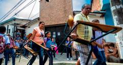 los niños con sus padres llevando los pupitres. 