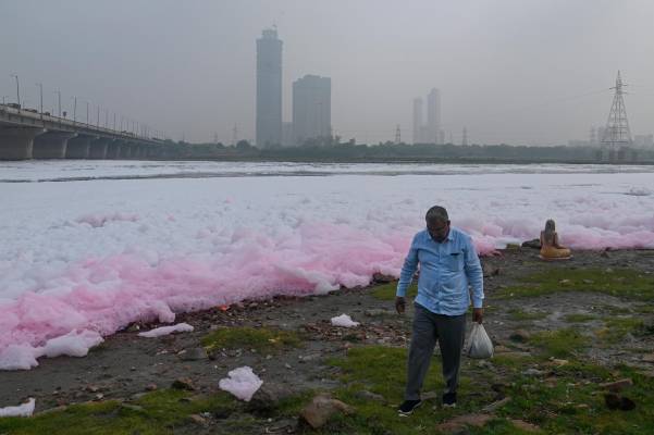 Un hombre camina a orillas del río Yamuna cubierto de espuma tóxica. Foto: Getty