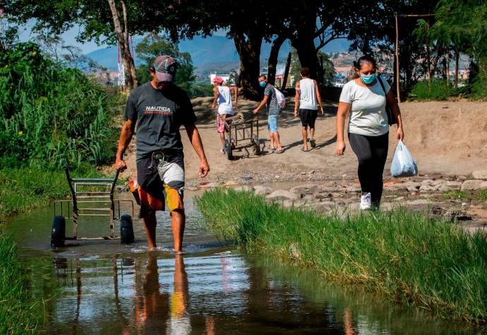 Los trocheros en carretilla cobran entre 15.000 y 20.000 pesos por llevar bolsos y paquetes por esos caminos clandestinos. Foto: Camilo Suárez