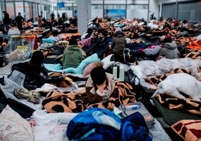 Centenares de personas descansan en un centro comercial destinado a la recepción temporal de refugiados que llegan a Polonia. Foto: Getty