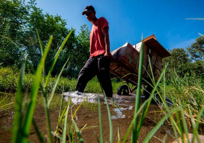 Los trocheros en carretilla cobran entre 15.000 y 20.000 pesos por llevar bolsos y paquetes por esos caminos clandestinos. Foto: Camilo Suárez