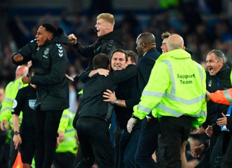 El colombiano Yerry Mina celebra en la banca con sus compañeros y el técnico Frank Lampard tras la victoria que los salvó del descenso. FOTO: TOMADA DE TWITTER @EVERTON