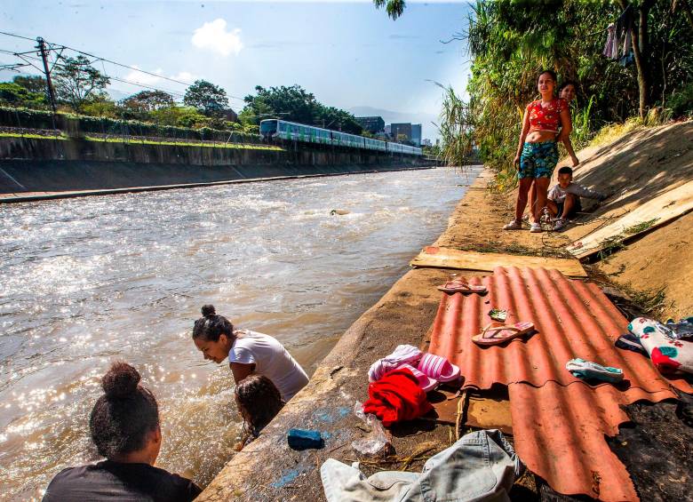 La rutina de la familia varada en Medellín incluye baños en el río, donde también lavan la ropa. Armaron las carpas bajo un árbol para resguardarse de la lluvia. FOTO ESNEYDER GUTIÉRREZ CARDONA