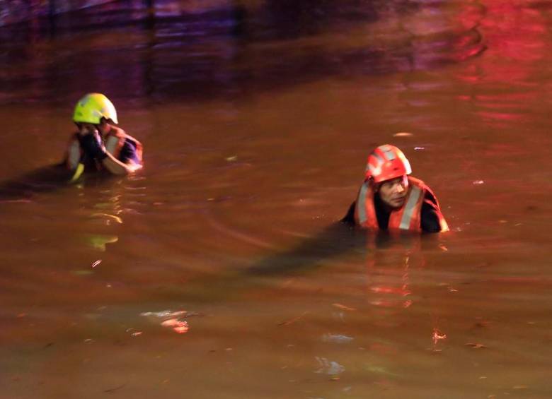 Durante las maniobras de rescate, los socorristas tuvieron que nadar en una calle inundada hasta los 1,55 metros para llegar al carro. FOTO CAMILO SUÁREZ