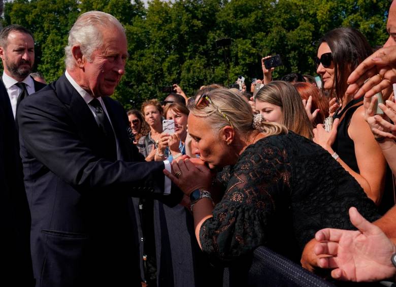 Tras ver las flores puestas en las rejas del palacio, el rey Carlos III se acercó al público y los saludo de mano. FOTO AFP