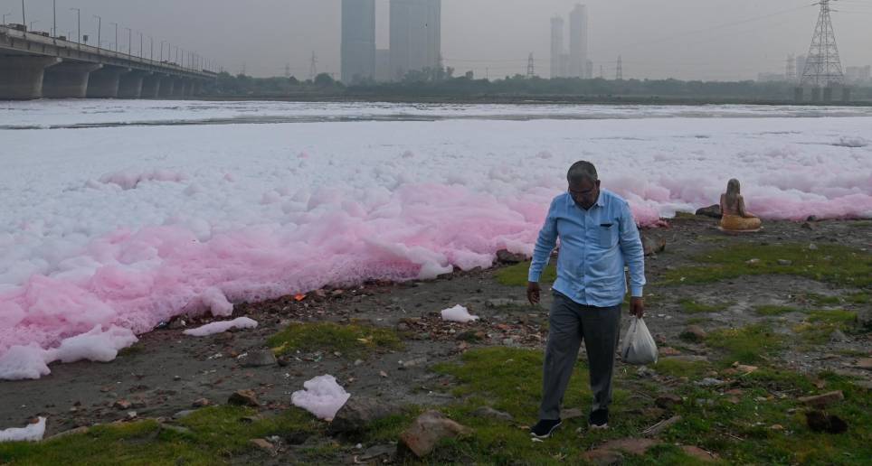 Un hombre camina a orillas del río Yamuna cubierto de espuma tóxica. Foto: Getty