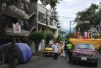 En el Barrio La Milagrosa, de la comuna 9 de Medellín, la iglesia organizó una procesión solitaria donde imparte la palabra acompañada de la policía. Los feligreses salen a los balcones al paso de la procesión. Foto: Edwin Bustamante.