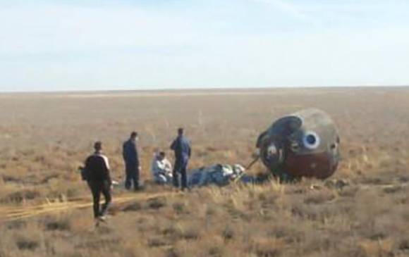 Aleksei Ovchinin y Nick Hague, tras ser sacados de la cápsula, que aterrizó en la estepa kazaja. FOTO REUTERS