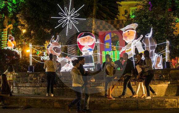 Las personas se aglomeran en torno al pesebre, que es el montaje principal del alumbrado