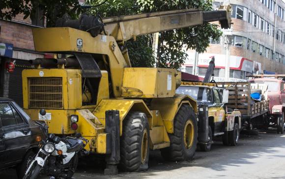En Barrio Triste, centro de Medellín, un grúa telescópica reposa cerca al viaducto del Metro (izquierda); en Belén Rincón, comuna 16, un taxi que obstruye el paso de los peatones ajusta meses esperando ser arreglado (centro) y en la Iguaná, otro taxi desbaratado espera ser vendido por partes (derecha) . FOTOs Julio césar herrera