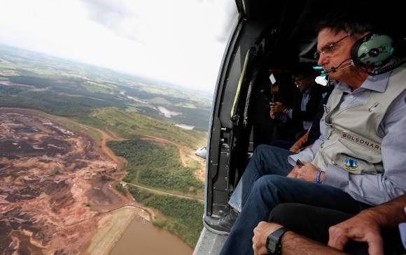 En la foto cedida por la presidencia de Brasil se observa al mandatario, Jair Bolsonaro mientras sobrevuela la zona afectada por una avalancha tras la rotura de una represa minera. Foto: EFE.