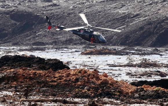 Un helicóptero busca sobrevivientes entre el río de lodo que cayó tras la ruptura de la represa. FOTO EFE