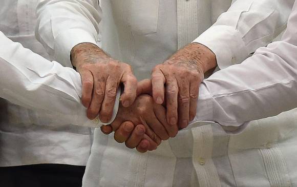 Las manos del presidente Juan Manuel Santos y de alias “Timochenko” de las Farc, se entrelazaron, afianzadas por las de Raúl Castro, el presidente cubano. FOTO afp