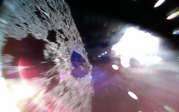 Imagen en color capturada mientras un explorador se mueve (durante un salto) en la superficie de Ryugu. La mitad izquierda de la imagen es la superficie del asteroide. La región blanca brillante es provocada por la luz solar. Foto: JAXA Imagen en color capturada mientras un explorador se mueve (durante un salto) en la superficie de Ryugu. La mitad izquierda de la imagen es la superficie del asteroide. La región blanca brillante es provocada por la luz solar. Foto: JAXA