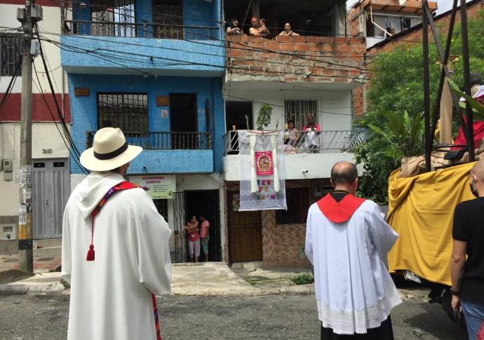 En el Barrio La Milagrosa, de la comuna 9 de Medellín, la iglesia organizó una procesión solitaria donde imparte la palabra acompañada de la policía. Los feligreses salen a los balcones al paso de la procesión. Foto: Edwin Bustamante.