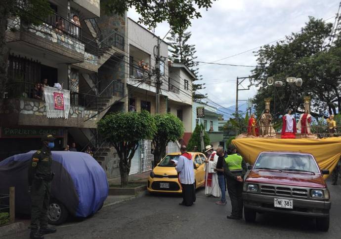 En el Barrio La Milagrosa, de la comuna 9 de Medellín, la iglesia organizó una procesión solitaria donde imparte la palabra acompañada de la policía. Los feligreses salen a los balcones al paso de la procesión. Foto: Edwin Bustamante.