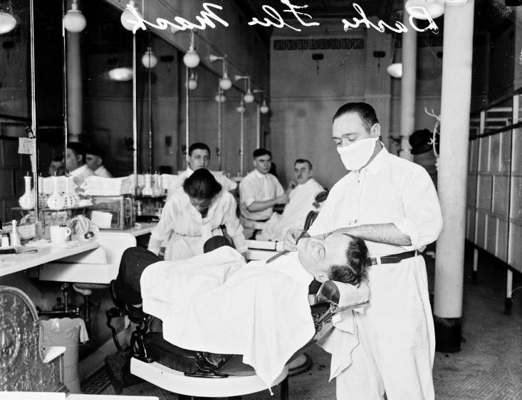 Este barbero trabaja con su tapabocas en 1918. La imagen fue tomada en Chicago, Estados Unidos. FOTO Getty