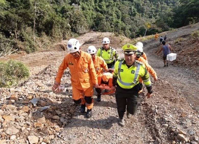 La Policía y los cuerpos de socorro ayudan a pasar a una persona que llegó enferma al derrumbe. FOTO cortesía policía de tránsito