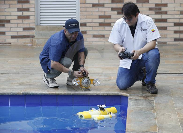 El profesor Carlos Alberto Valencia (derecha) y el auxiliar de laboratorio Luis Felipe Arias prueban los minisubmarinos que crearon en una de las piscinas del Pascual Bravo. FOTO MANUEL SALDARRIAGA