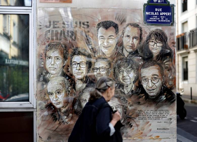 Una mujer pasa junto a un cuadro del artista y pintor francés Christian Guemy, en homenaje a los miembros del periódico Charlie Hebdo que fueron asesinados. FOTO AFP