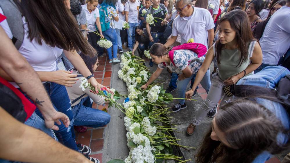 Flores y pancartas fueron llevados por la comunidad universitaria en un acto simbólico para rechazar los actos violentos.